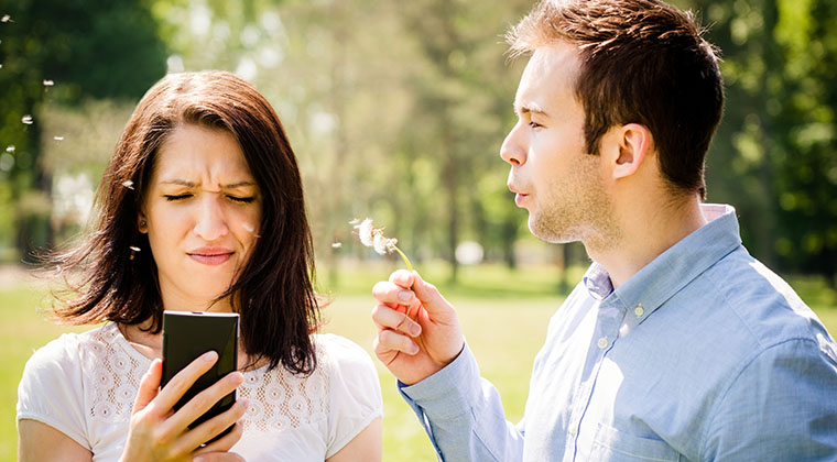young-man-blowing-dandelion-face-angry-woman-holding-mobile-phone